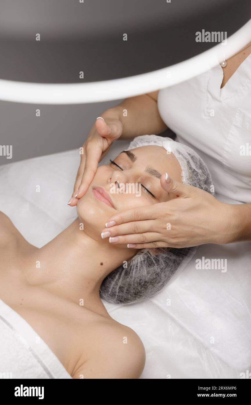 Beautician giving facial massage to woman with hands Stock Photo