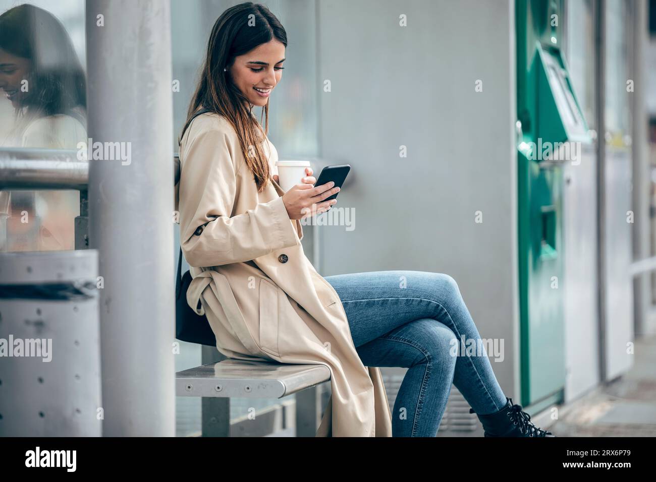 Happy woman sitting on bench and using smart phone Stock Photo