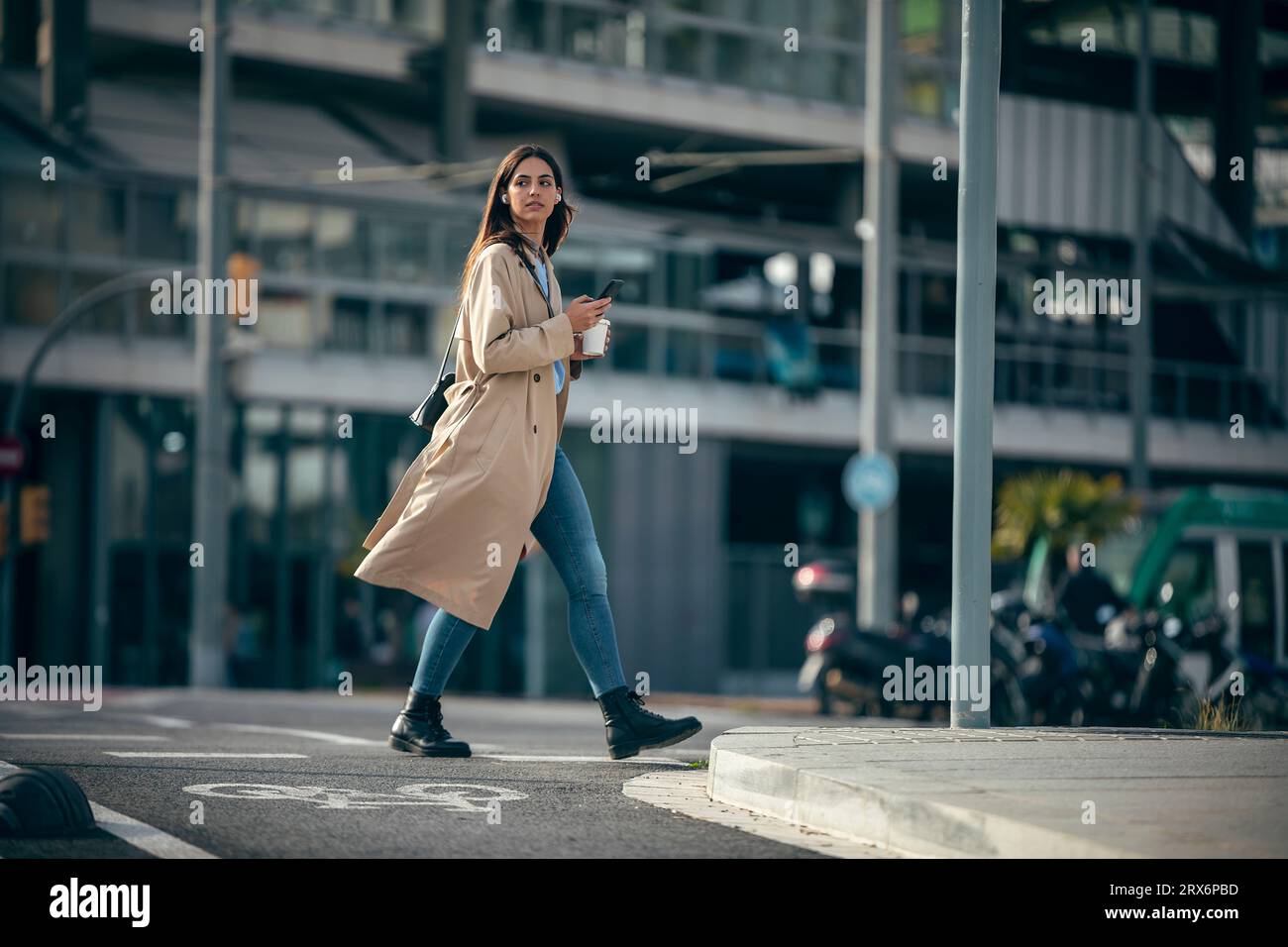 Young woman walking with smart phone and coffee cup at street Stock Photo