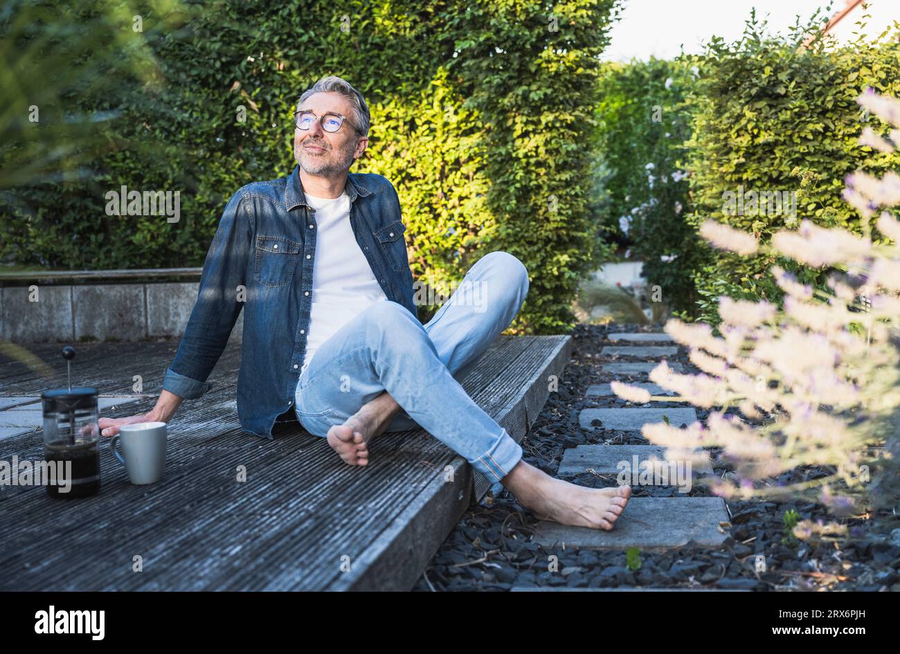 Mature man day dreaming sitting with coffee on porch Stock Photo