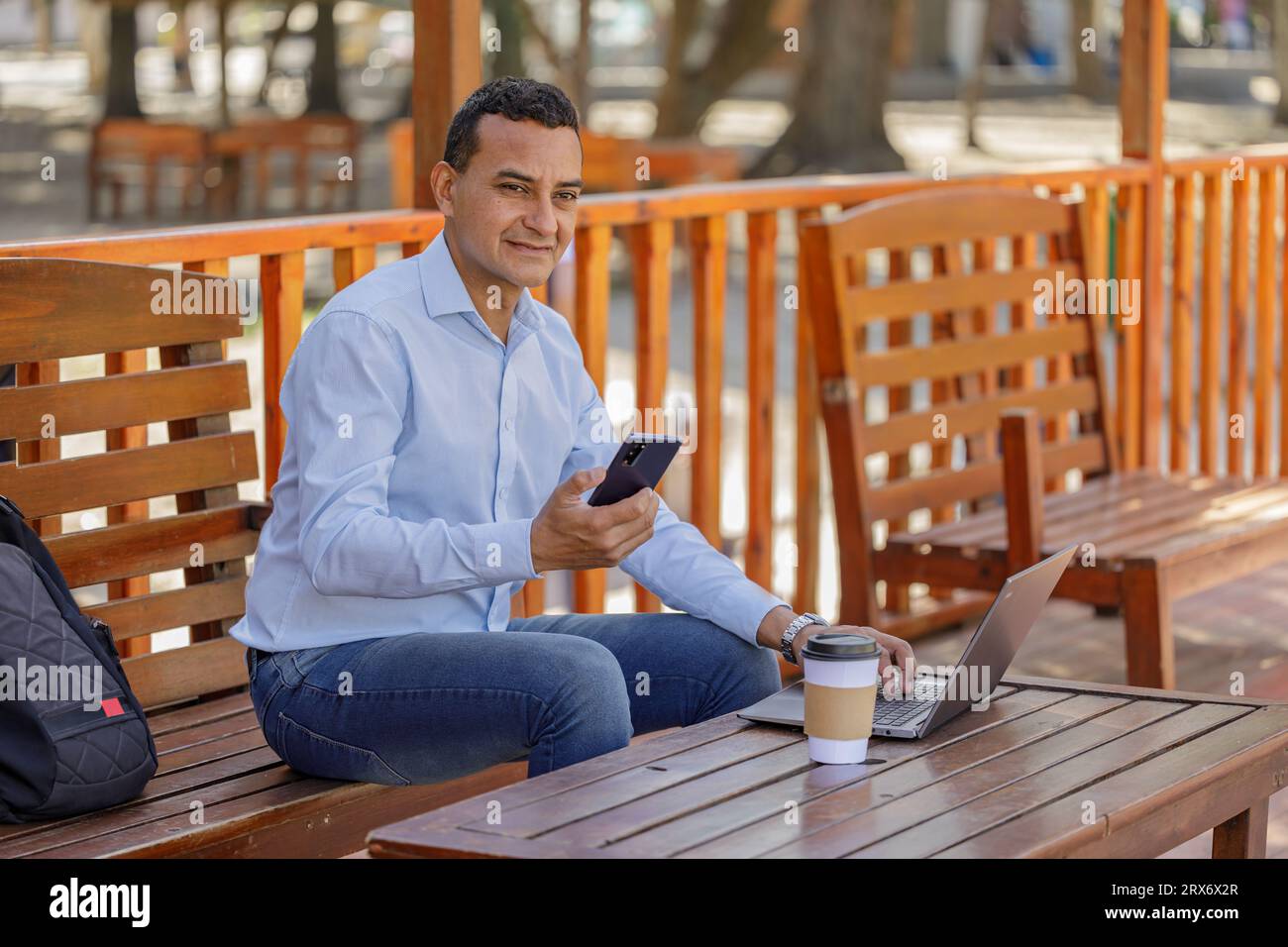 Latin man using a laptop while drinking coffee in a bar. Stock Photo