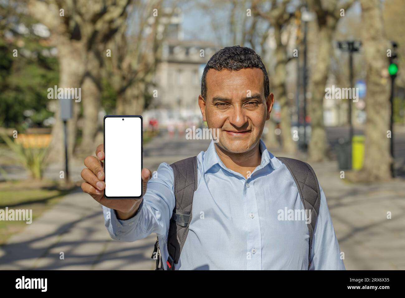 Latin man in a city shows the screen of his mobile phone. Stock Photo