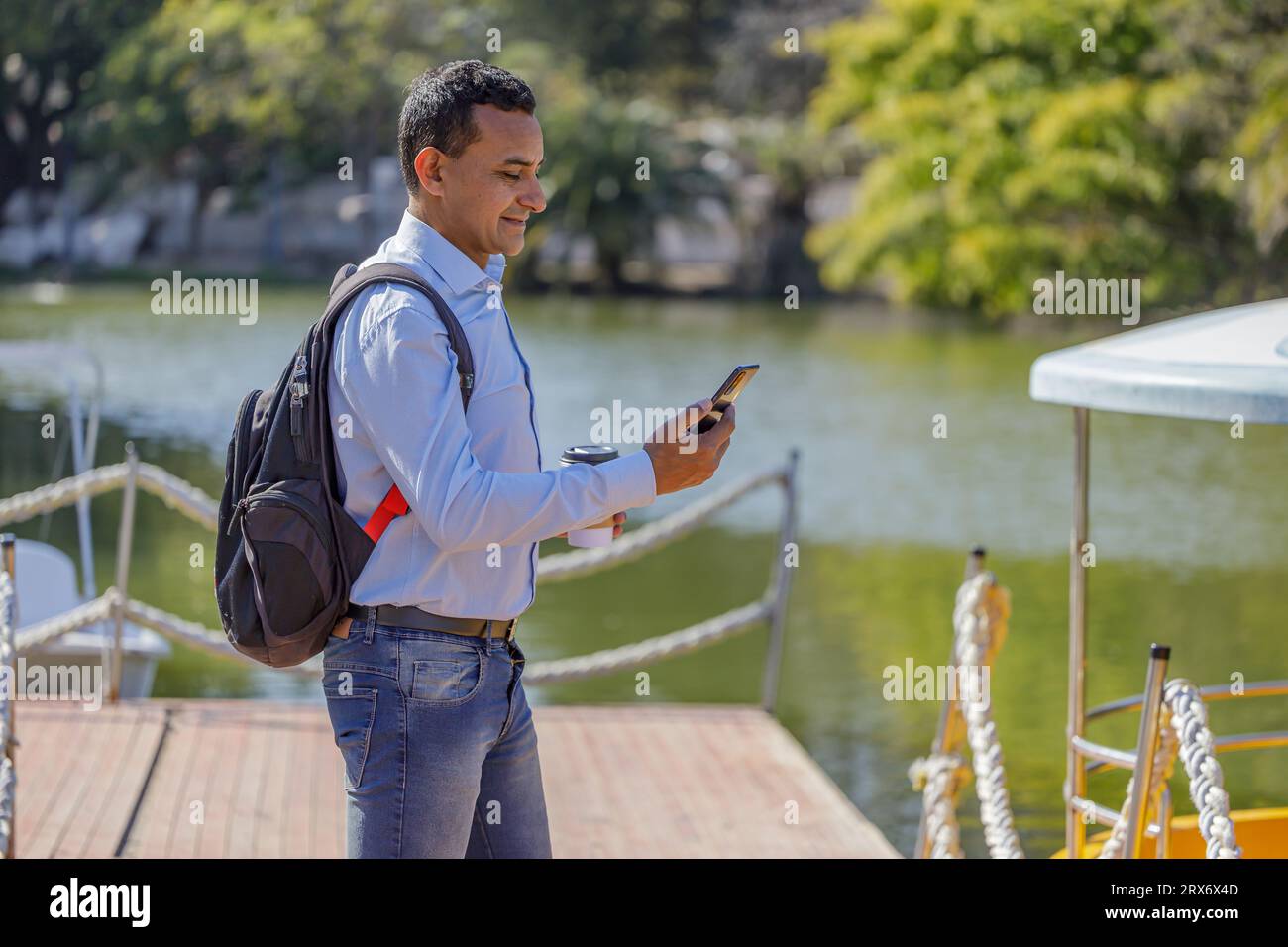 Latin man using a mobile phone on a dock. Stock Photo