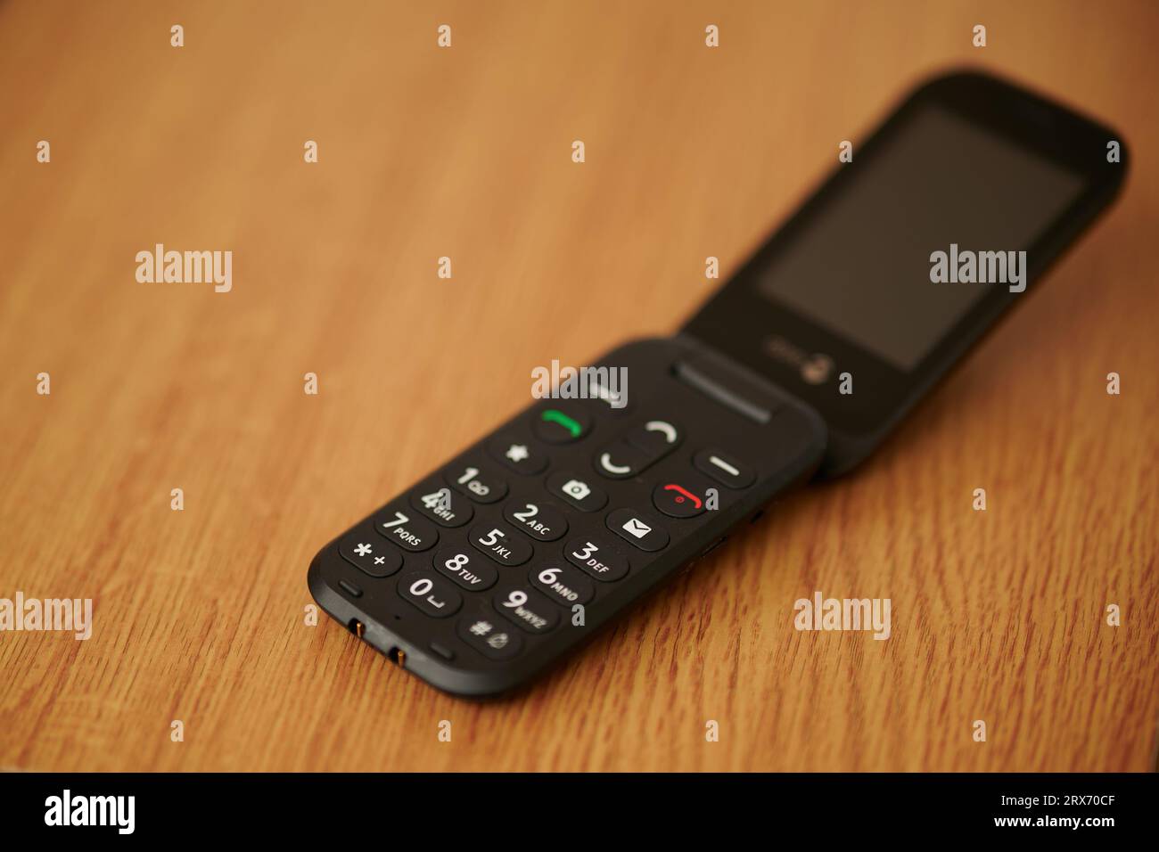 16 Sep 2023 - England  UK : Old style dumb mobile phone clam phone on wooden table Stock Photo