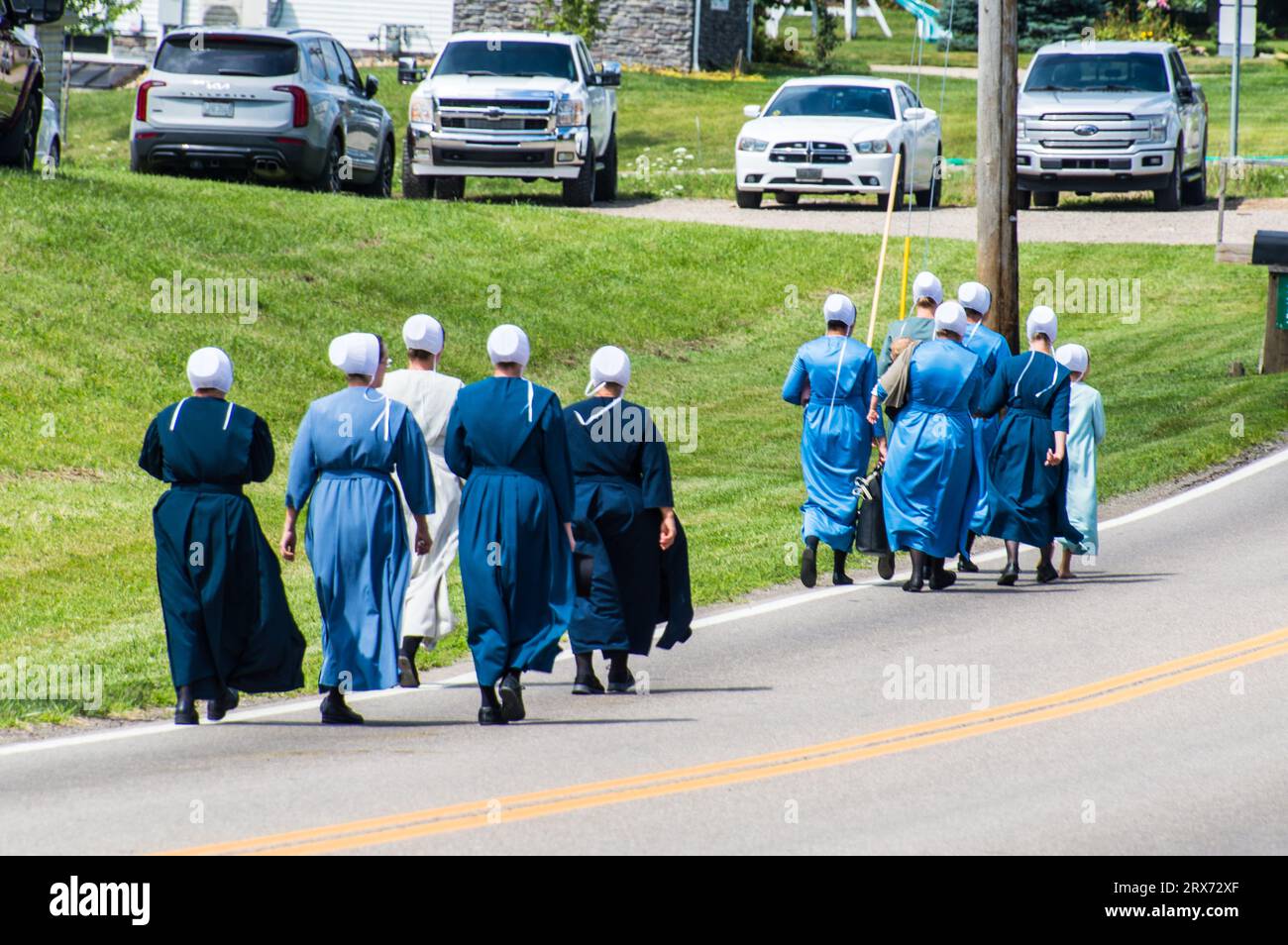 Group of Amish women in simple plain coloured clothing walking on the road Stock Photo