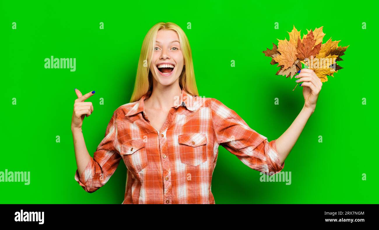 Autumn fashion for women. Happy girl in plaid shirt with autumn leaves. Smiling woman in fashionable wear pointing finger at maple leafs. Season sale Stock Photo