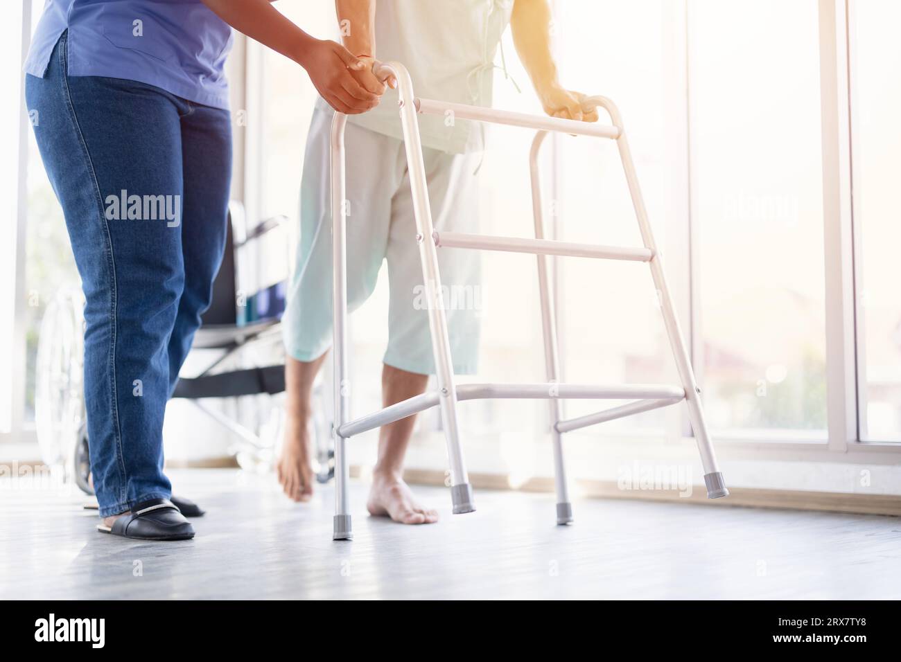 Patient muscle recovery walking training practice using walker with physiotherapist care help support Stock Photo
