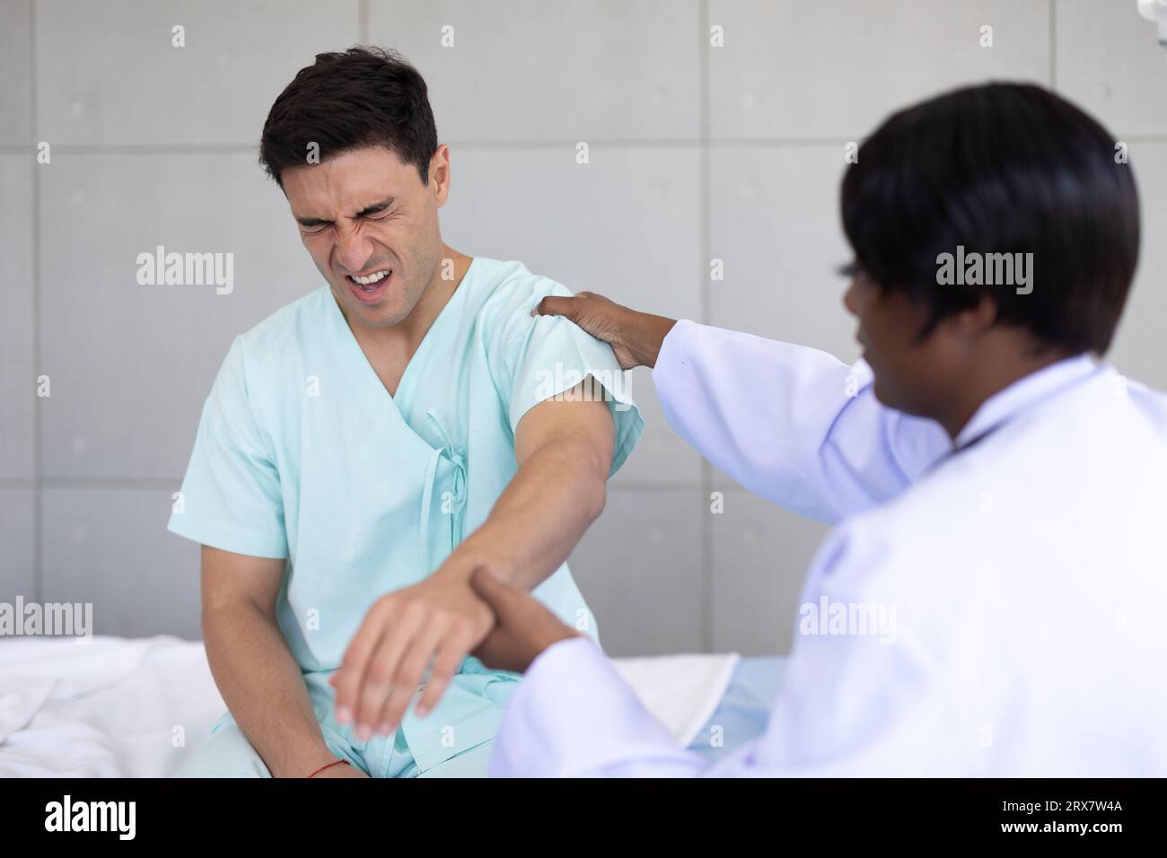 Patient sport male meeting physiotherapist doctor for muscle joint pain physical therapist recovery in hospital clinic Stock Photo