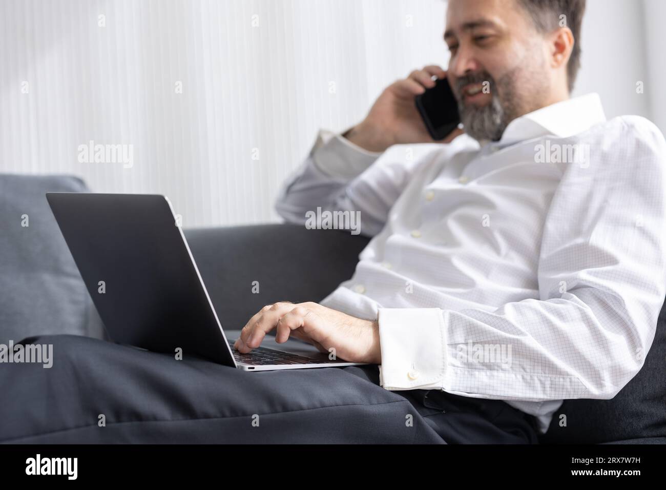 Happy senior manager business man relax at office sofa calling with friend while using laptop comfortable success people lifestyle Stock Photo