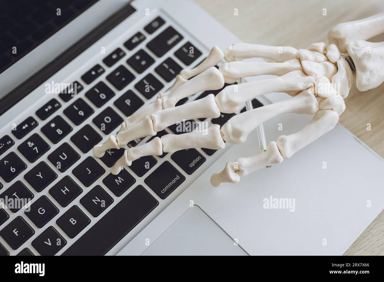 Office syndrome concept. Skeleton hand bone joint wrist pain physical effect when typing laptop computer Stock Photo