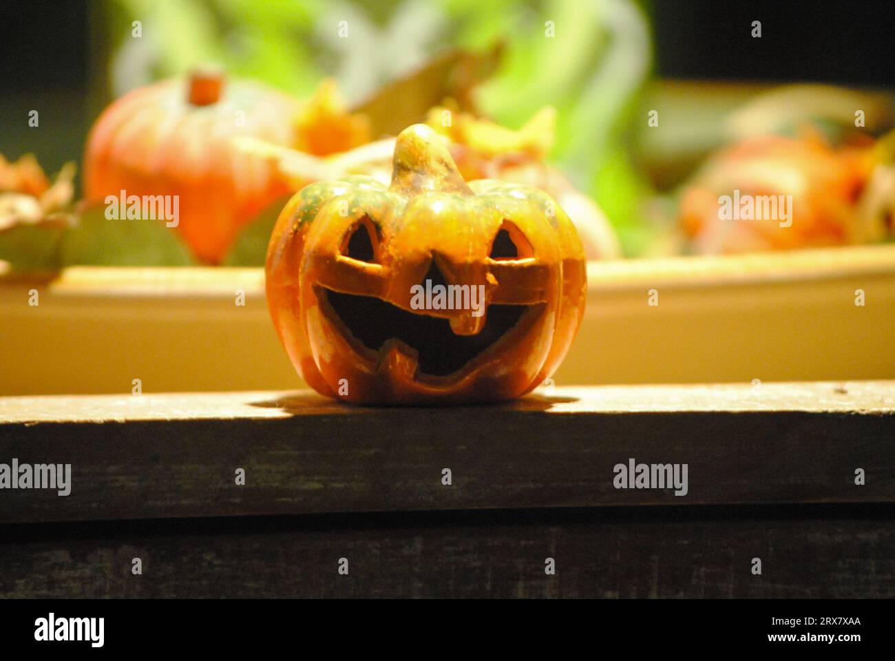 Small smiling pumpkin in shadows with others in background as Halloween time Stock Photo