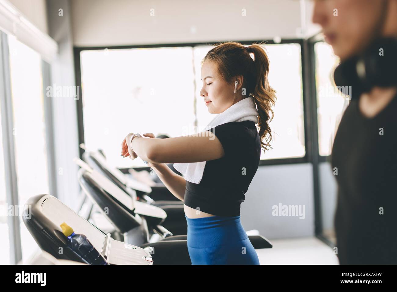 People running on a treadmill in health club using Smart Watch tracking pulse and training time for health goal Stock Photo