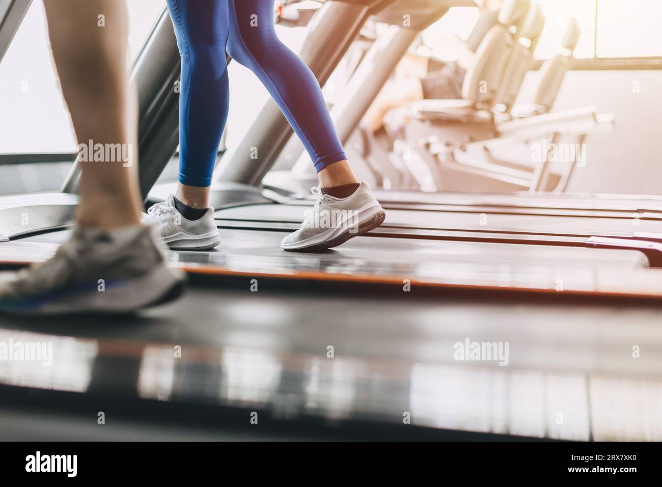 People running on a treadmill in health club. Sport fitness healthcare and healthy lifestyle concept. Stock Photo