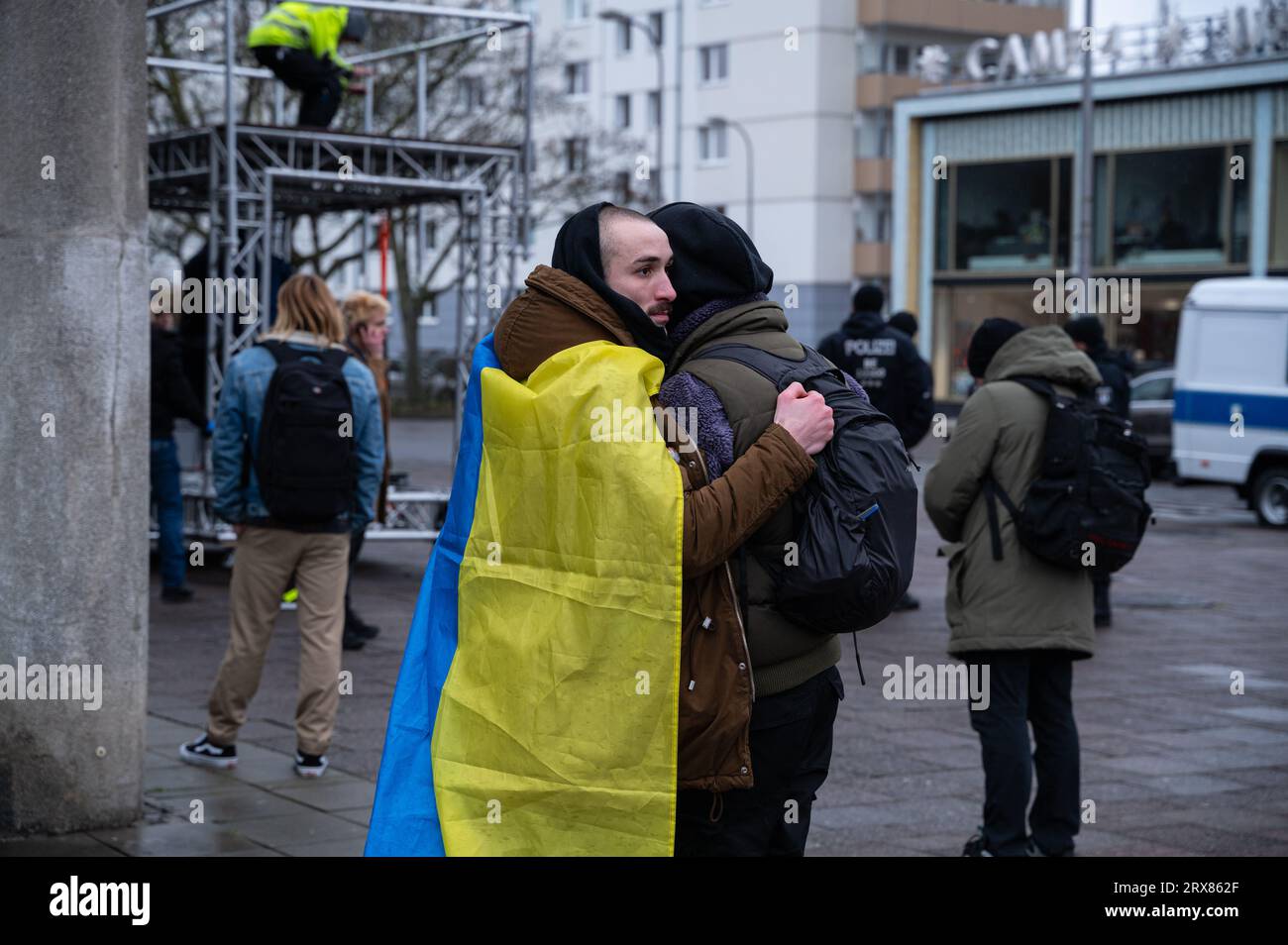 24.02.2023, Berlin, Germany, Europe - Three participants stand closely embraced in front of Café Moskau, protesting against the war in the Ukraine. Stock Photo