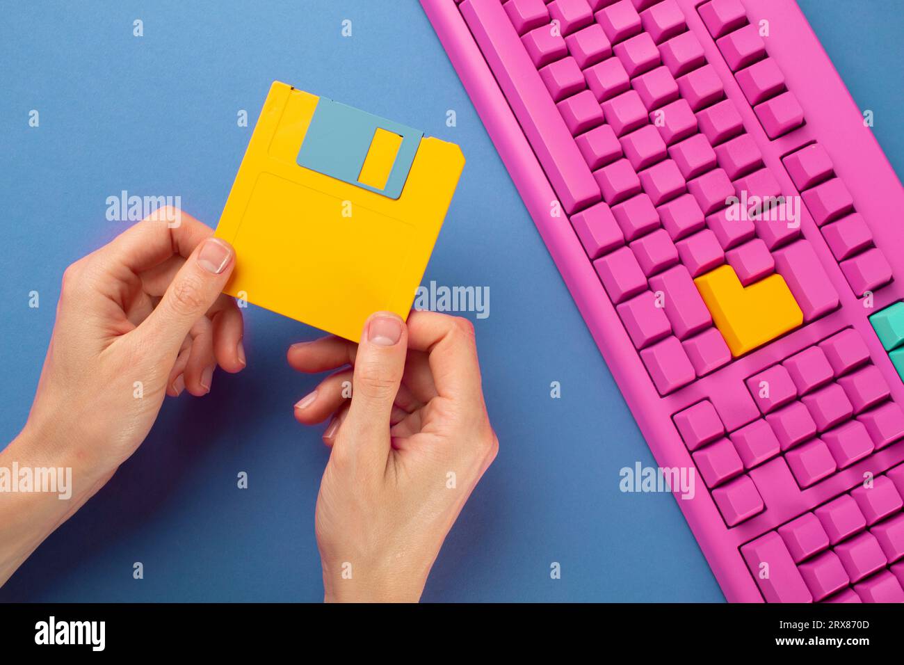 Hand holding floppy disk on color keyboard background, technology