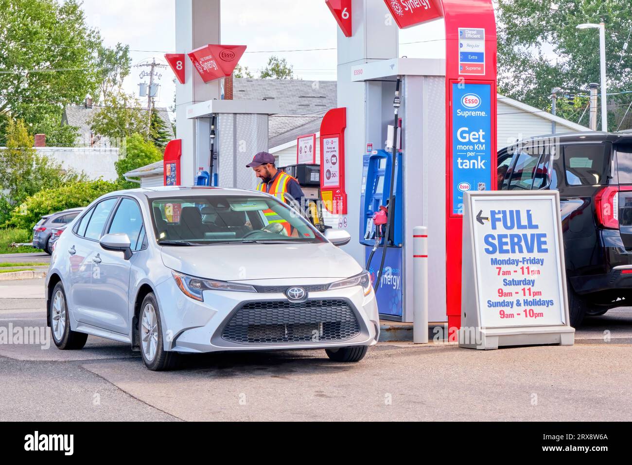 Employee pumps gas at a full service fuel station. Stock Photo