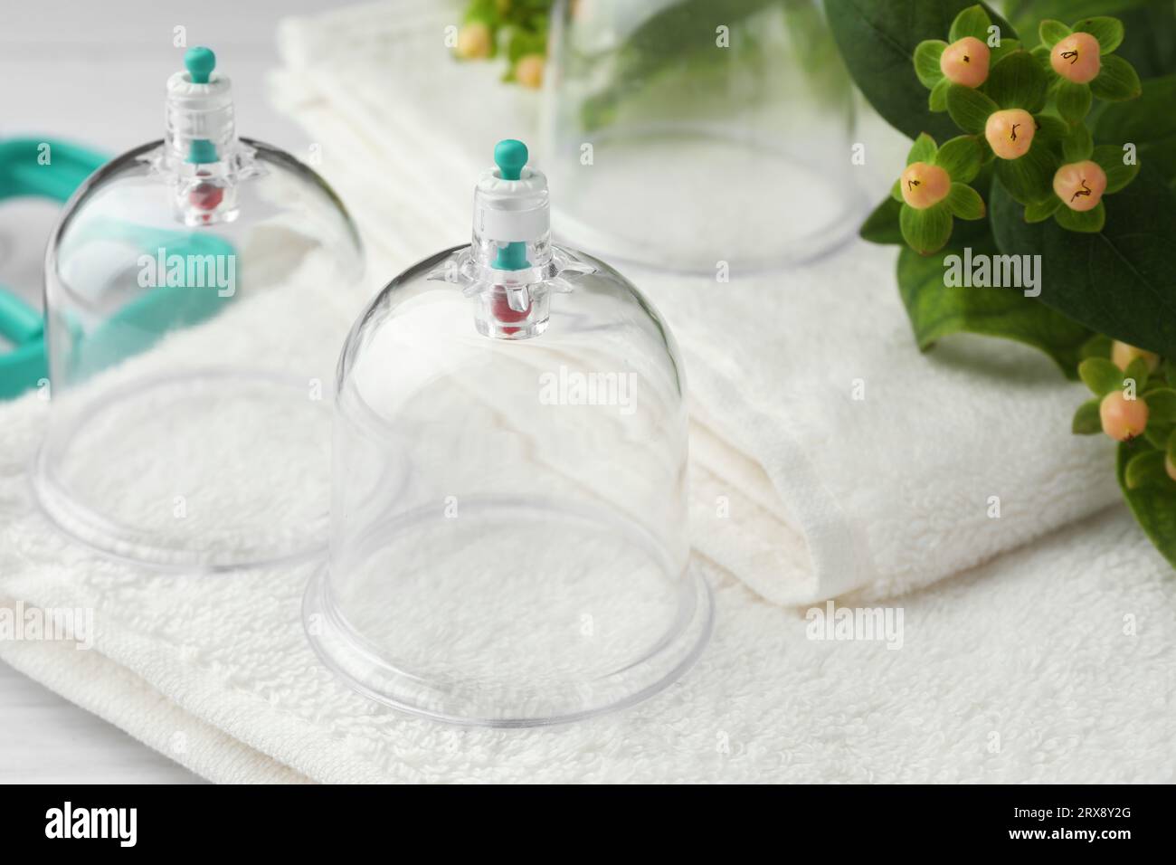 Cupping therapy. Plastic cups, towels and hypericum perforatum berries on table, closeup Stock Photo