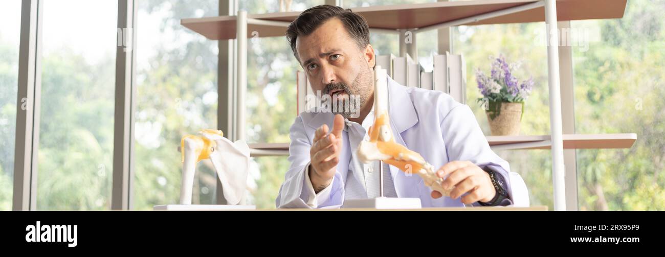 Bone orthopedic doctor explaining about orthopedic surgery with skeleton model. Healthcare and medicine concept with senior expertise bone physician. Stock Photo