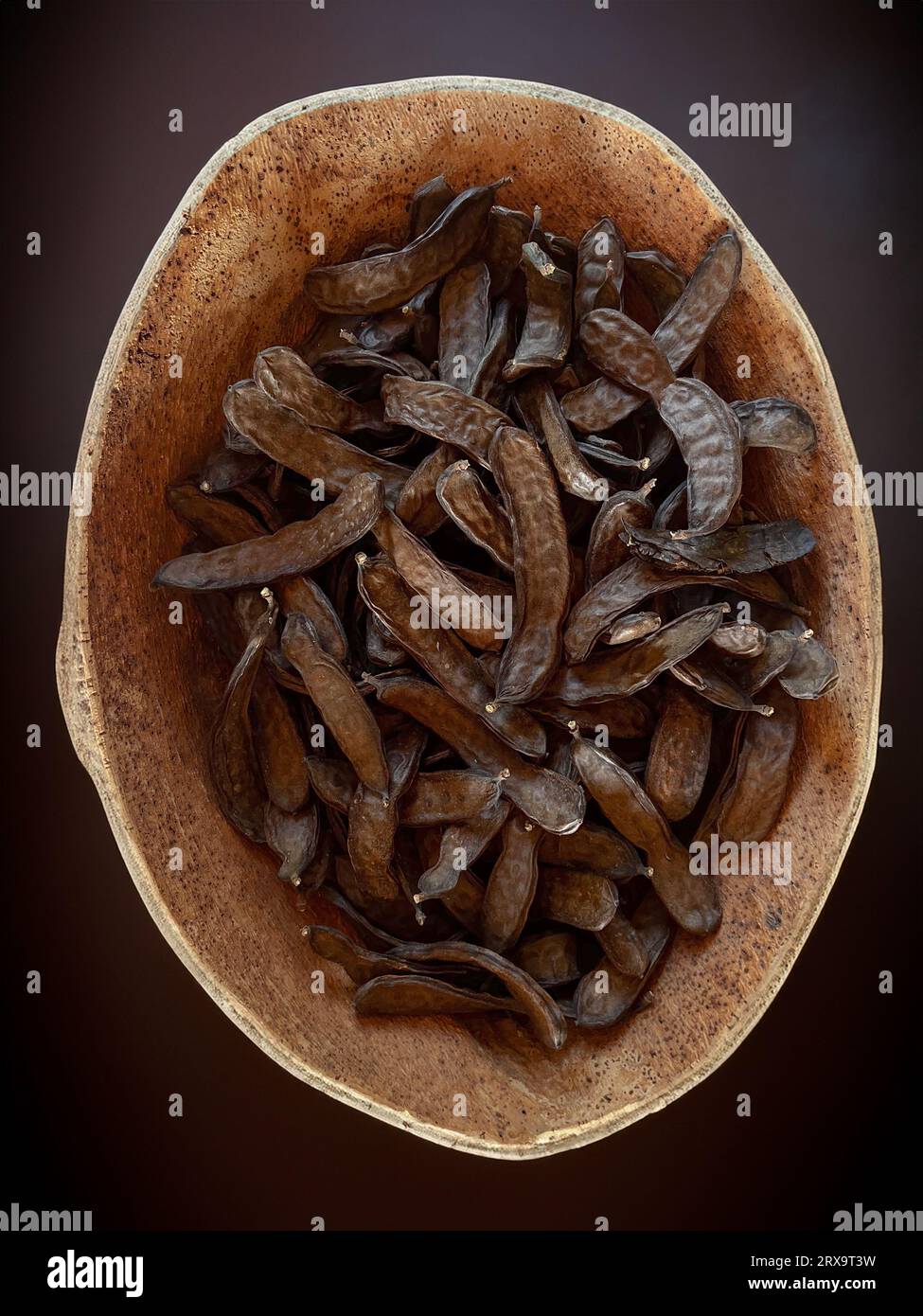 Dried carob pods closeup in a cork container.Isolated carob and carob