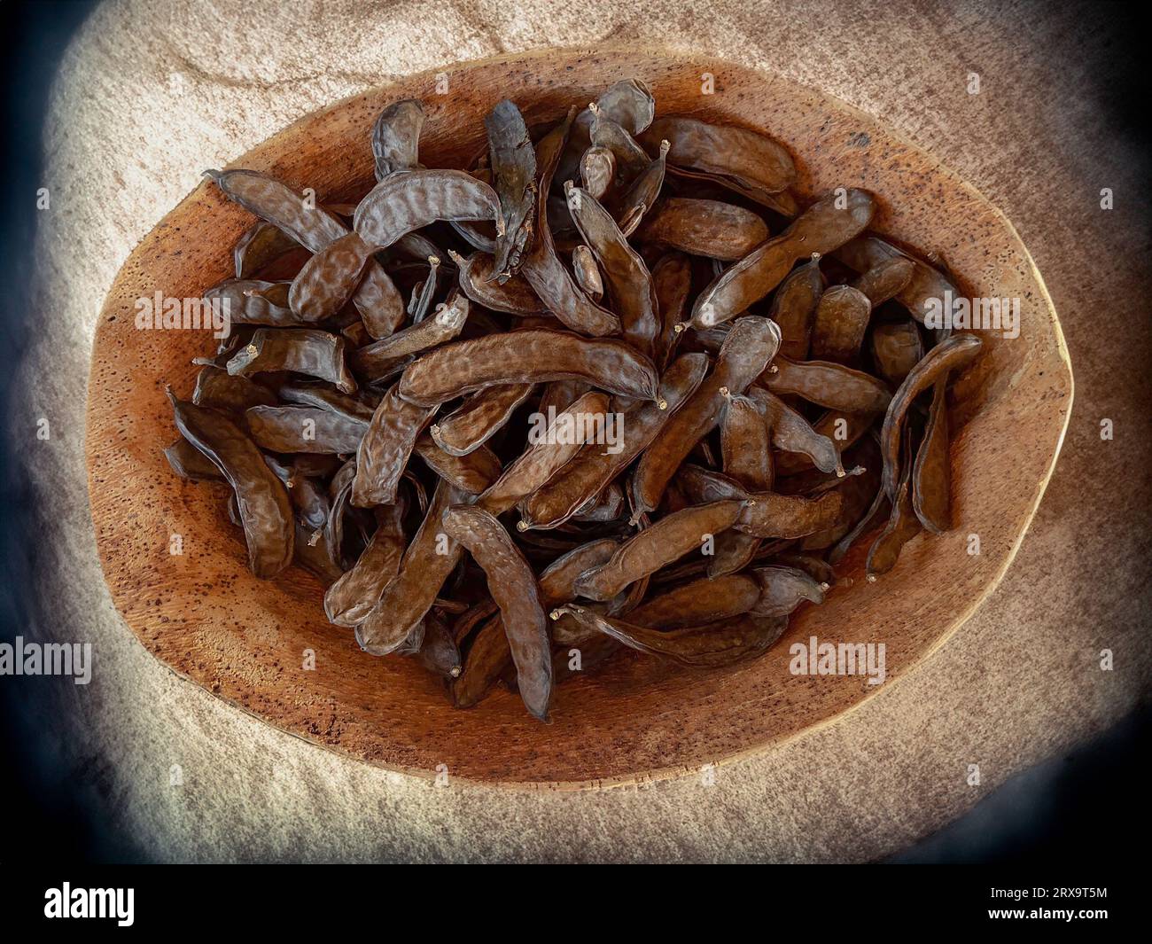 Dried carob pods closeup in a cork container.Isolated carob and carob