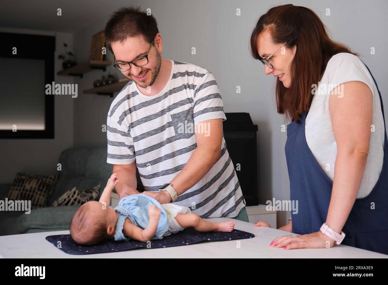 Happy Caucasian parents changing their one month daughter diaper at