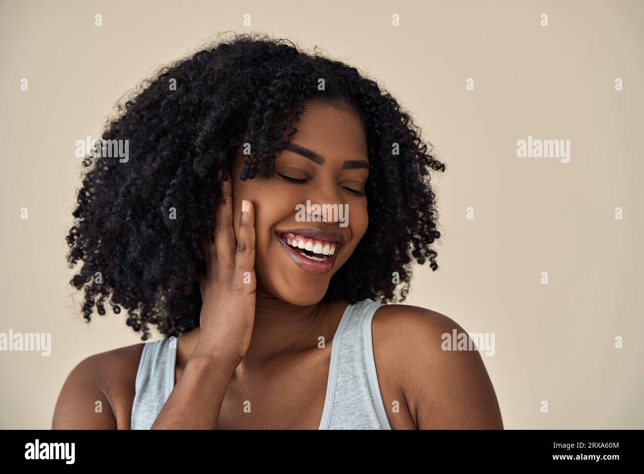 Happy young African woman touching face advertise skin care at beige ...