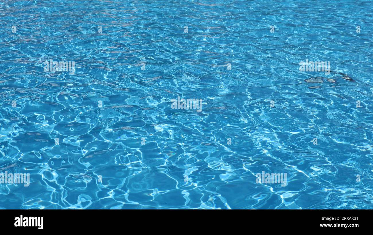 transparent turquoise water with quiet ripples as a bright colored background, the texture of the surface of water in a pool, sea or ocean Stock Photo