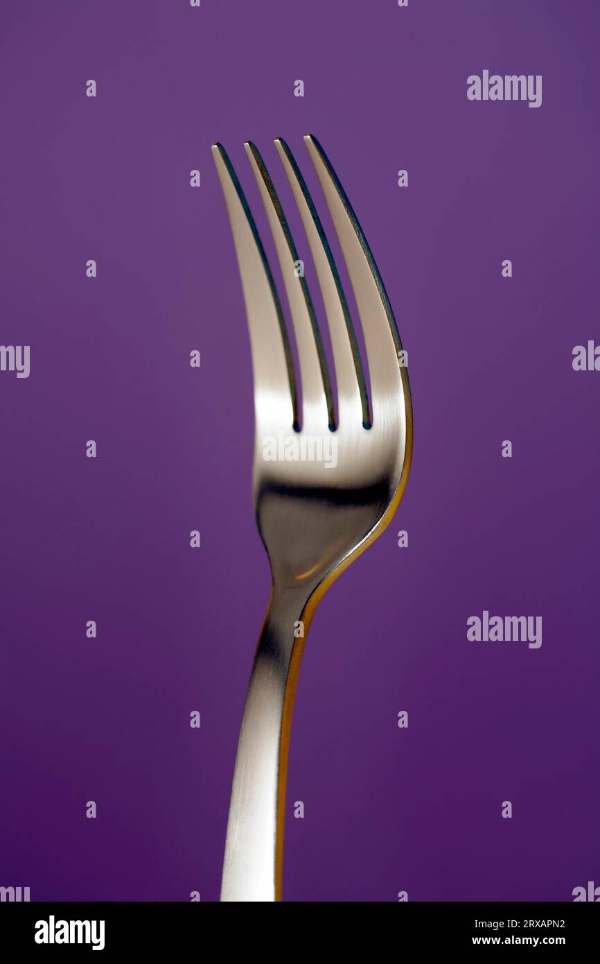 A fork against lila background Stock Photo