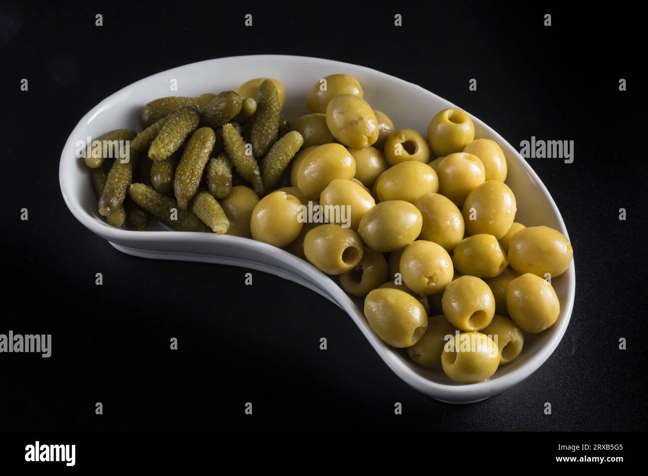 olives and pickles on a kidneyshaped tray, typical Spanish appetizer. the tray is placed on a