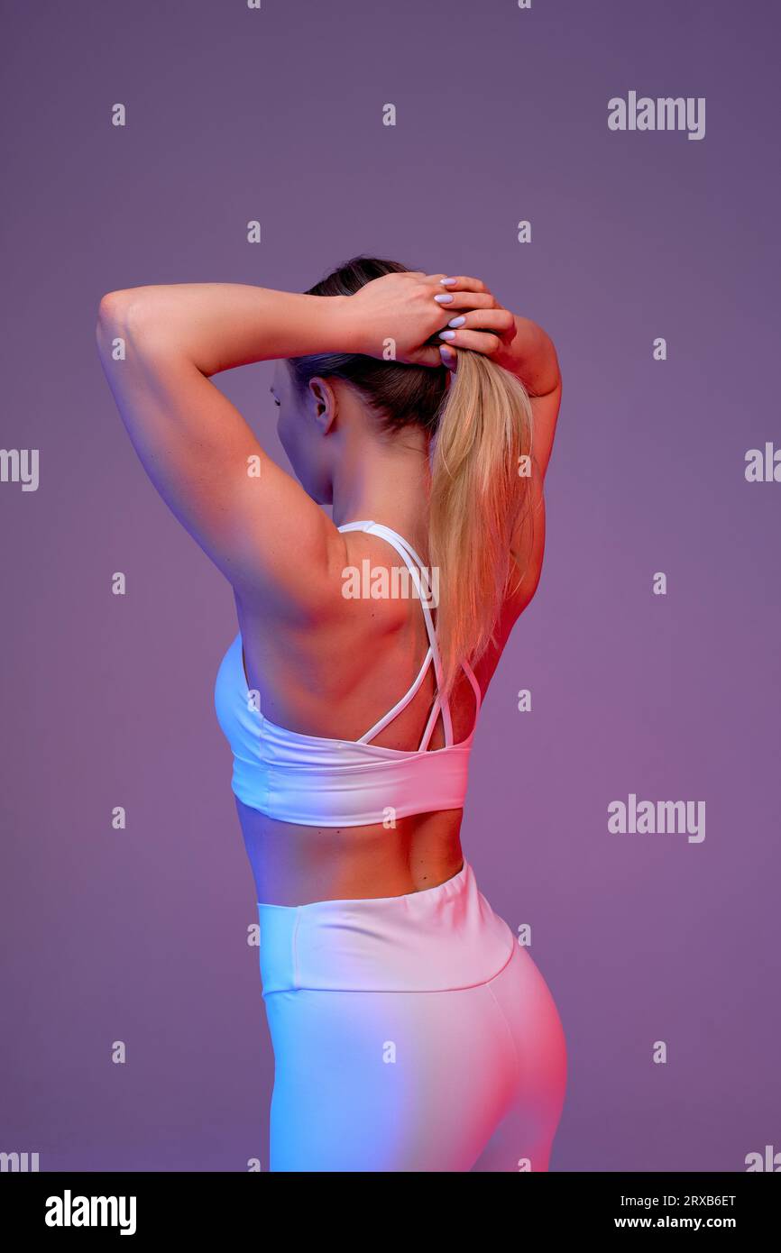 Back view of sexy sportswoman making ponytail. preparation for workout, back view shot, isolated purple, violet background Stock Photo