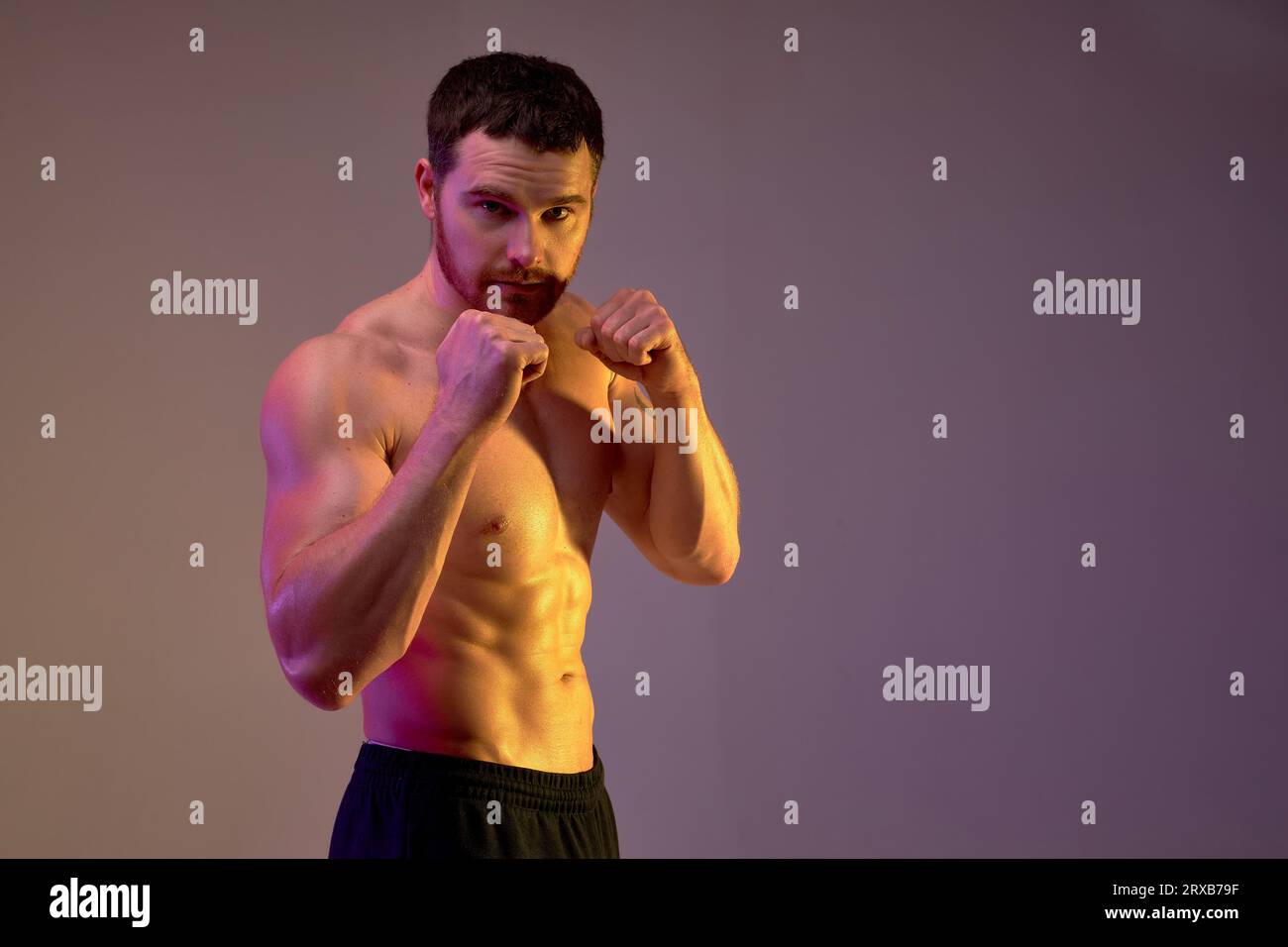young strong man standing in protection position and looking at the camera, isolated brown background. copy space. guy prepares for boxing competition Stock Photo