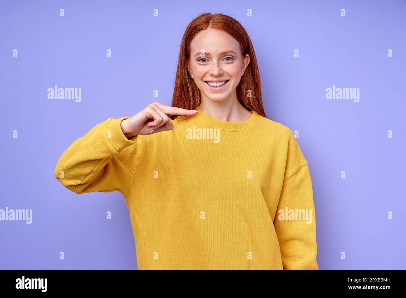 cheerful Caucasian woman with long red hair demonstrating the letter H