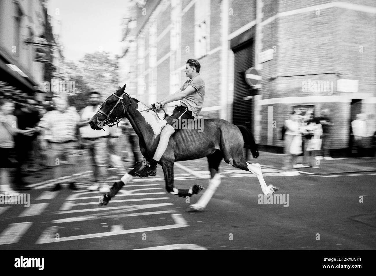 London black and white street photography: A youth rides a horse along Greek street in Soho, London, UK. Stock Photo