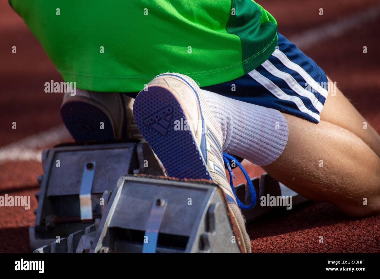 Young female track and field athlete with spikes by Adidas at the starting block before a sprint
