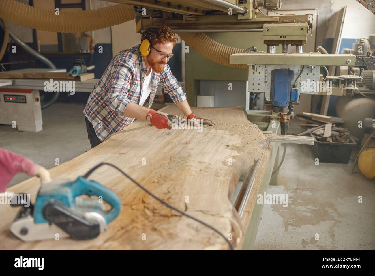 Carpenter is cleaning saw from sawdust with air compressor working in