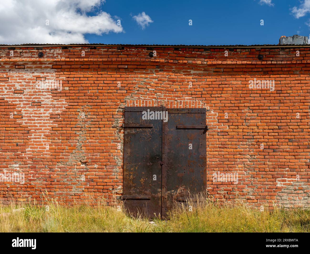 Abandoned brick building with a rusted metal door Stock Photo