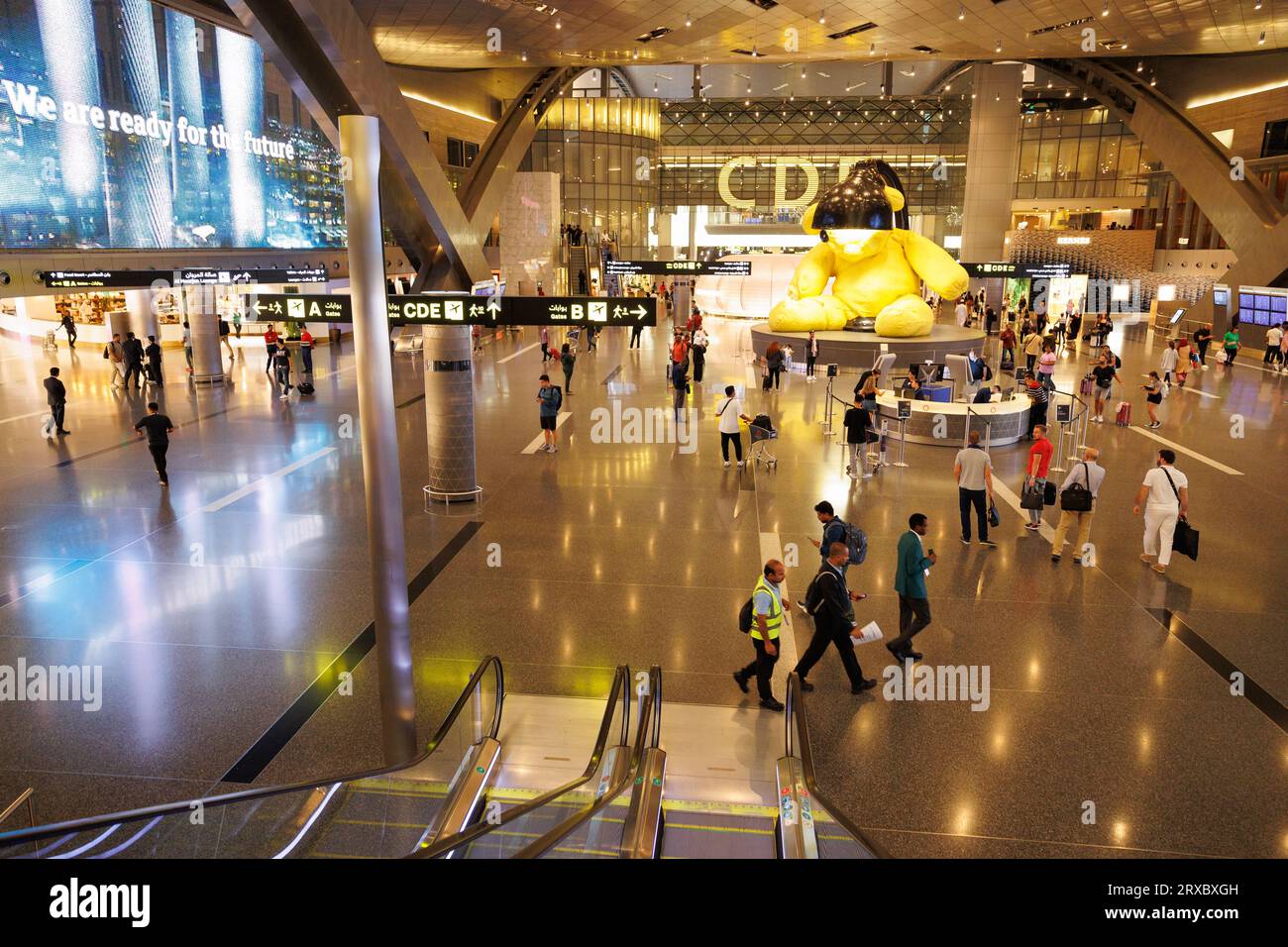 Travelers inspect the Lamp Bear sculpture by Swiss artist Urs Fischer in Hamad International Airport, Doha, Qatar. Stock Photo