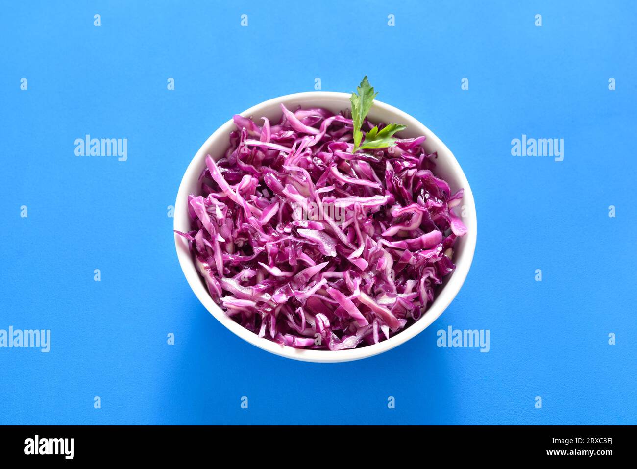 Red cabbage in bowl on blue background. Close up view Stock Photo