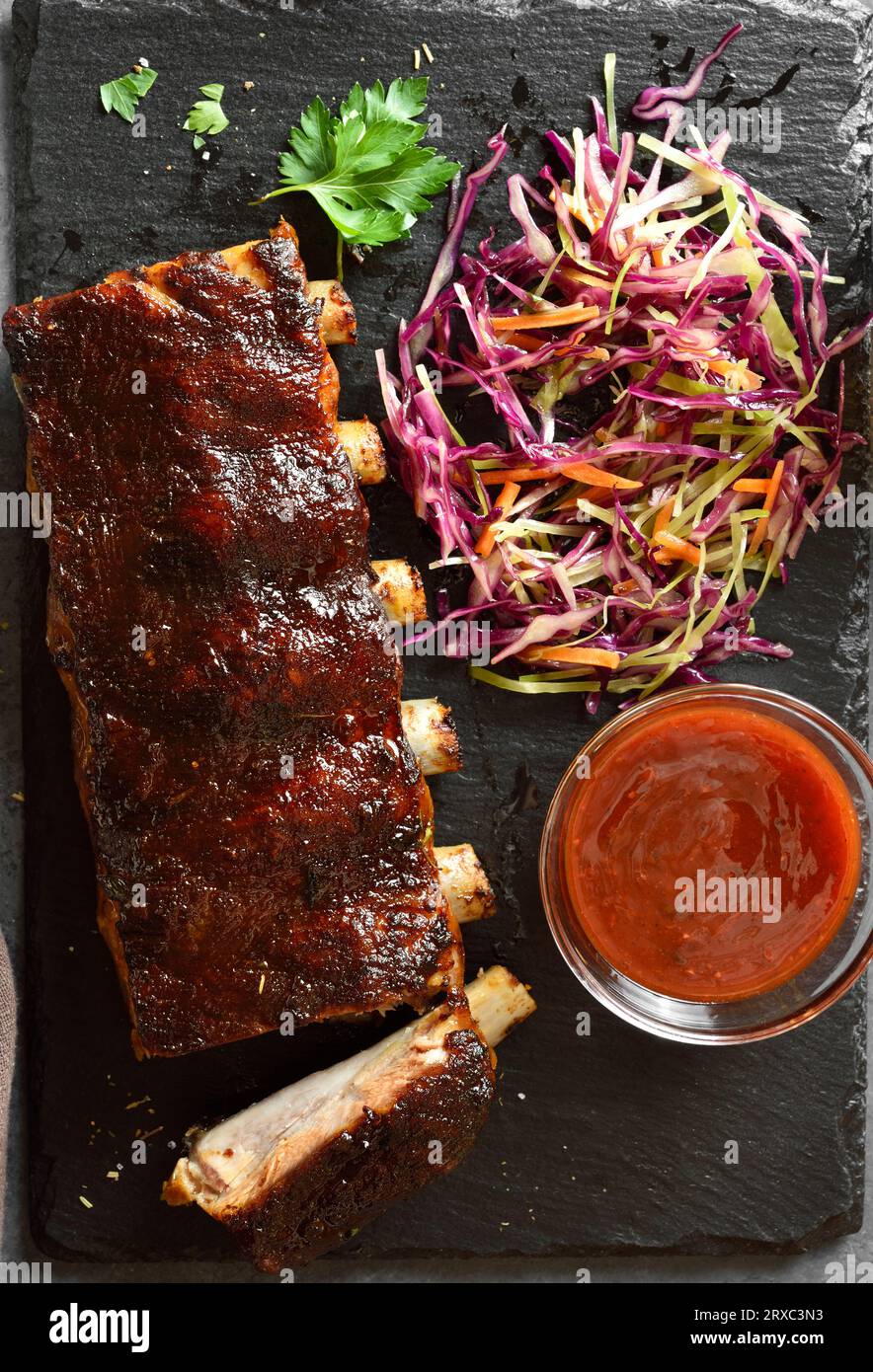 Spicy grilled spare ribs on board over dark stone background. Top view, flat lay Stock Photo