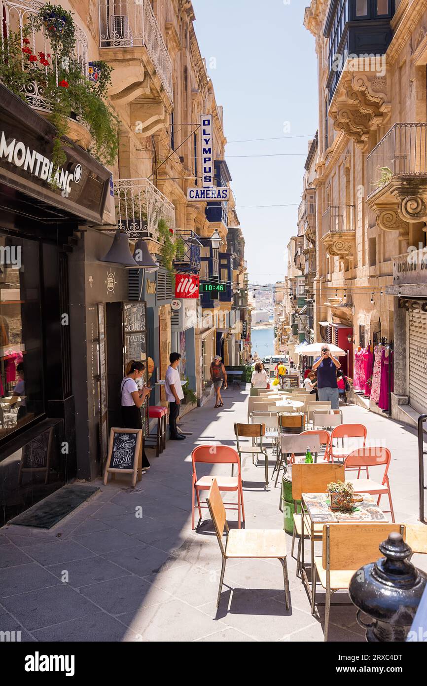 Valletta, Malta - 17 June 2023: Street with building and cafe tables at restaurants in Valletta, Malta. Stock Photo