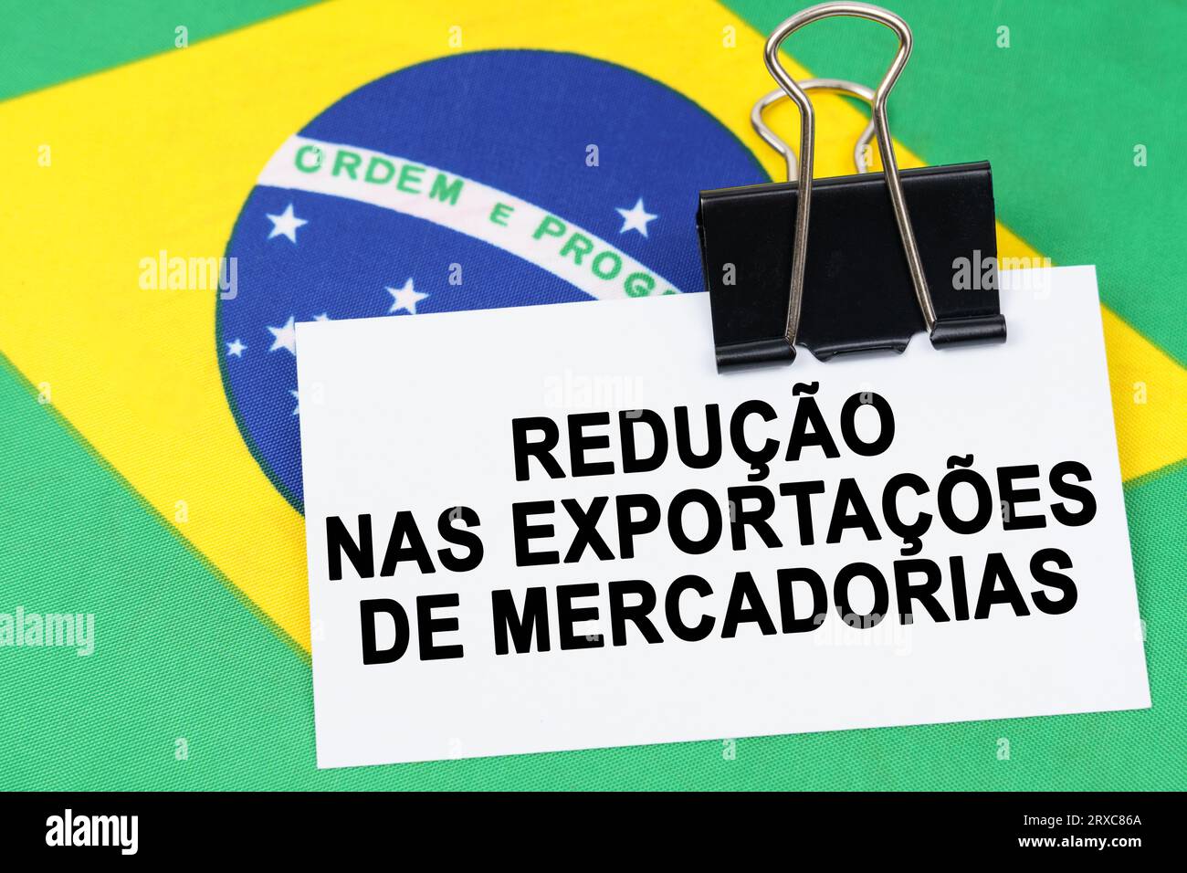 Economy and finance concept. On the flag of Brazil lies a business card with the inscription - reduction in exports of goods. Text in Portuguese. Stock Photo