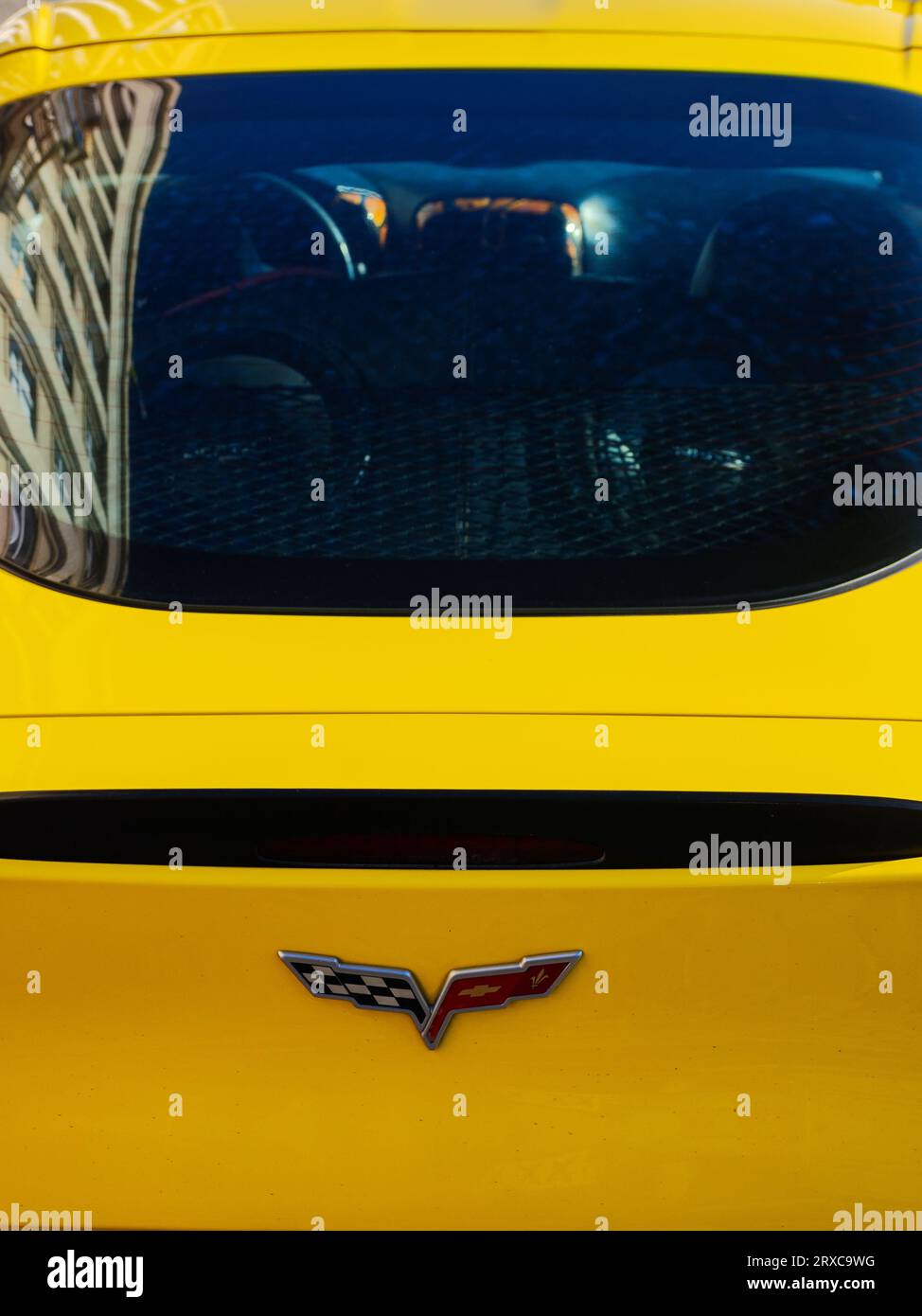 uzhgorod, ukraine - 31 oct 2021: chevrolet corvette logo on a trunk of a yellow sports car. outdoor closeup. old building reflecting in the rear windo Stock Photo
