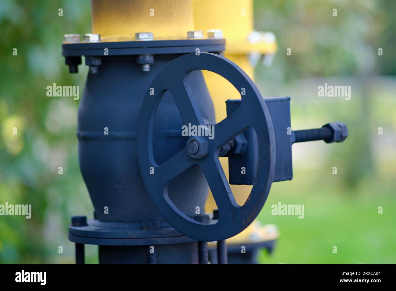 Fire extinguishing module with heat flow on gas pipes. Yellow gas pipe with valve on the background of green grass and trees Stock Photo