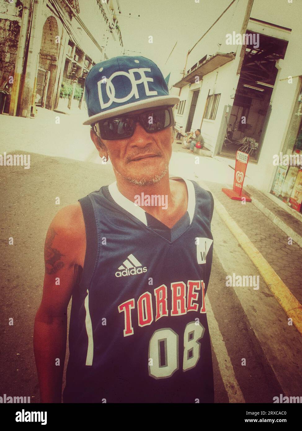 Cebu city, Philippines - September 28, 2013: Portrait of senior adult Filipino man wearing basketball shirt, baseball hat, tattooed, sunglasses. Stree Stock Photo