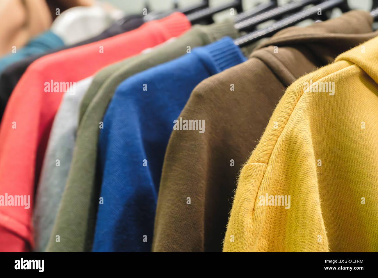 Fashion hoodie clothes on clothing rack Closeup of rainbow color choice ...