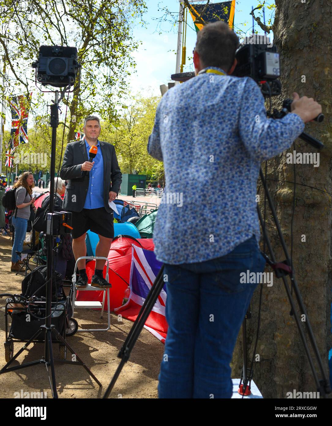 A Tv crew doing a piece to camera at the kings coronation build up on the Mall. With the reporter wearing shorts with his suit attire. Stock Photo