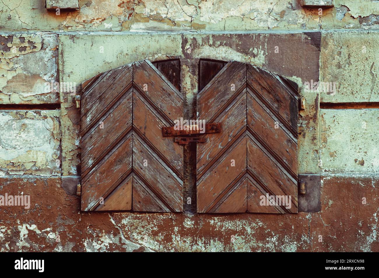 Old vintage small window with closed antique wooden shutters. Stock Photo