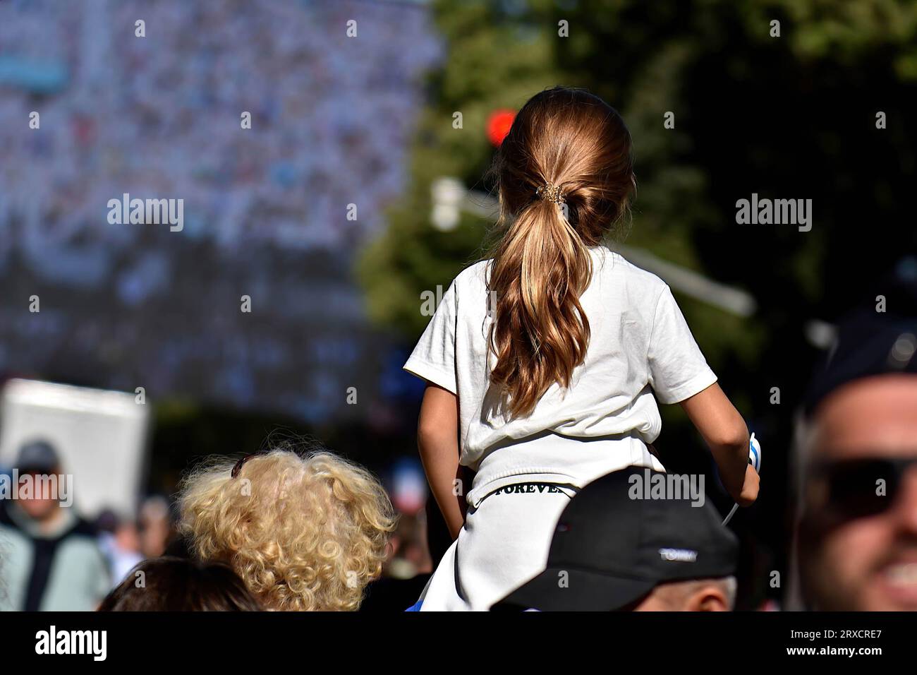 A child perched on his father's shoulders attend the mass given by Pope Francis at the Vélodrome on a super giant screen. Thousands of people came to see Pope Francis stroll in his “Papamobile” on Avenue du Prado, they attended the high mass on giant screens at the Vélodrome stadium. Stock Photo