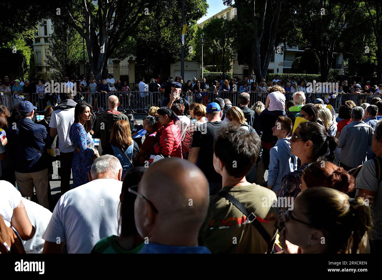 People gathered behind barriers wait to see Pope Francis pass in his “Papamobile”. Thousands of people came to see Pope Francis stroll in his “Papamobile” on Avenue du Prado, they attended the high mass on giant screens at the Vélodrome stadium. Stock Photo