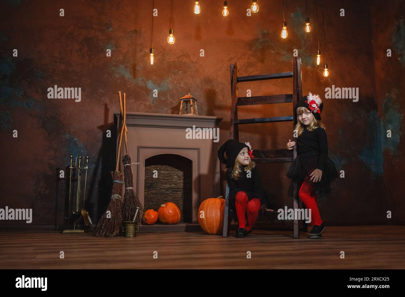 Girls in witch costumes near the fireplace on the stairs. There are